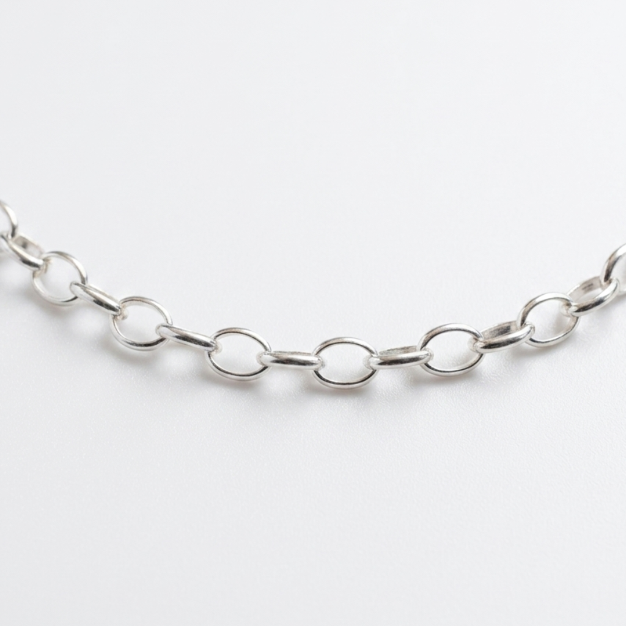 Freigestellte Nahaufnahme einer Gliederkette im Rolo-Stil (Ankerkette) aus hochglanzpoliertem 925er Silber auf weißem Hintergrund.