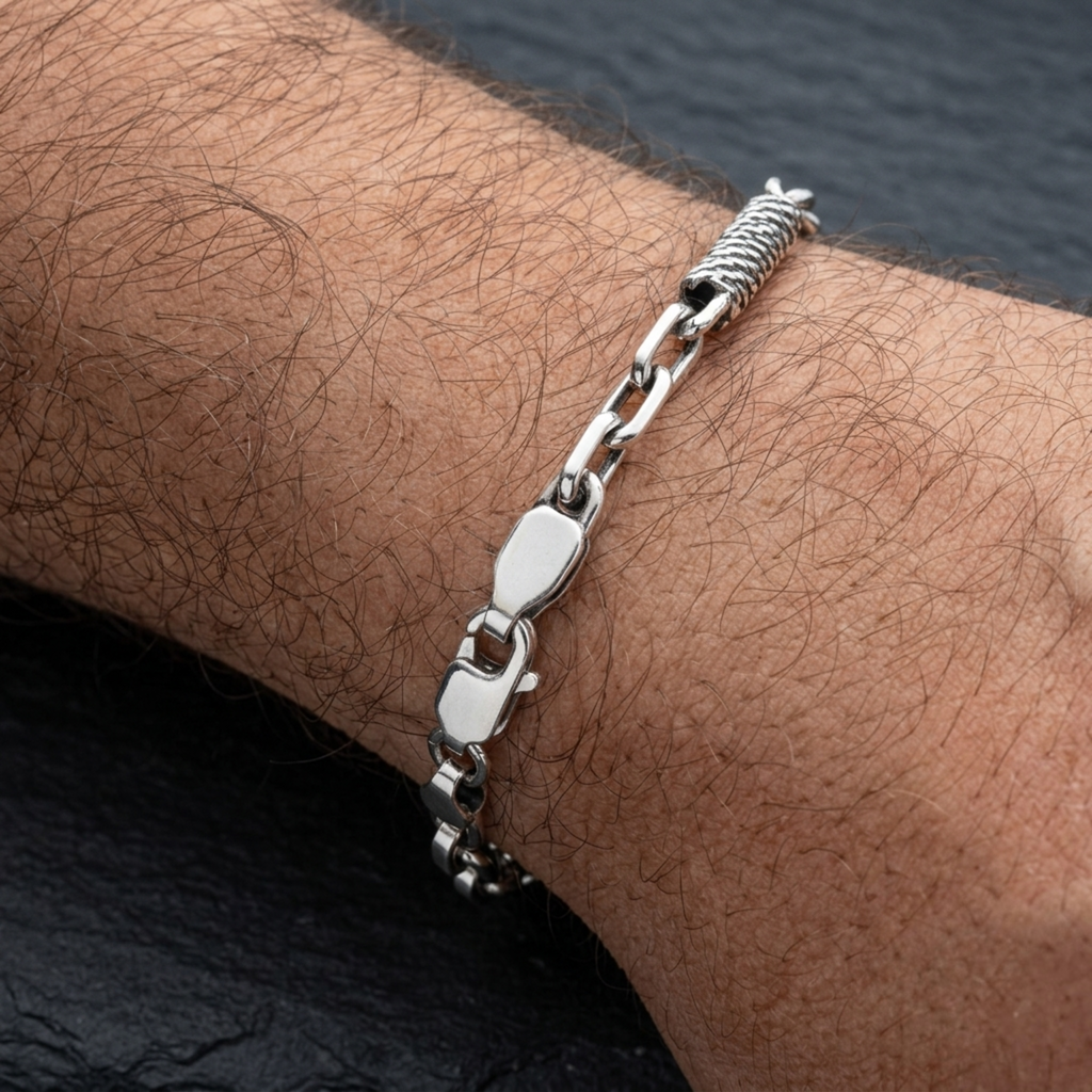Nahaufnahme eines Ankerarmbands aus 925er Sterlingsilber mit oxidierter Oberfläche am Handgelenk, gefertigt mit spiralförmigen Seildraht-Einsätzen, passenden Endkappen und einem robusten Karabinerverschluss.