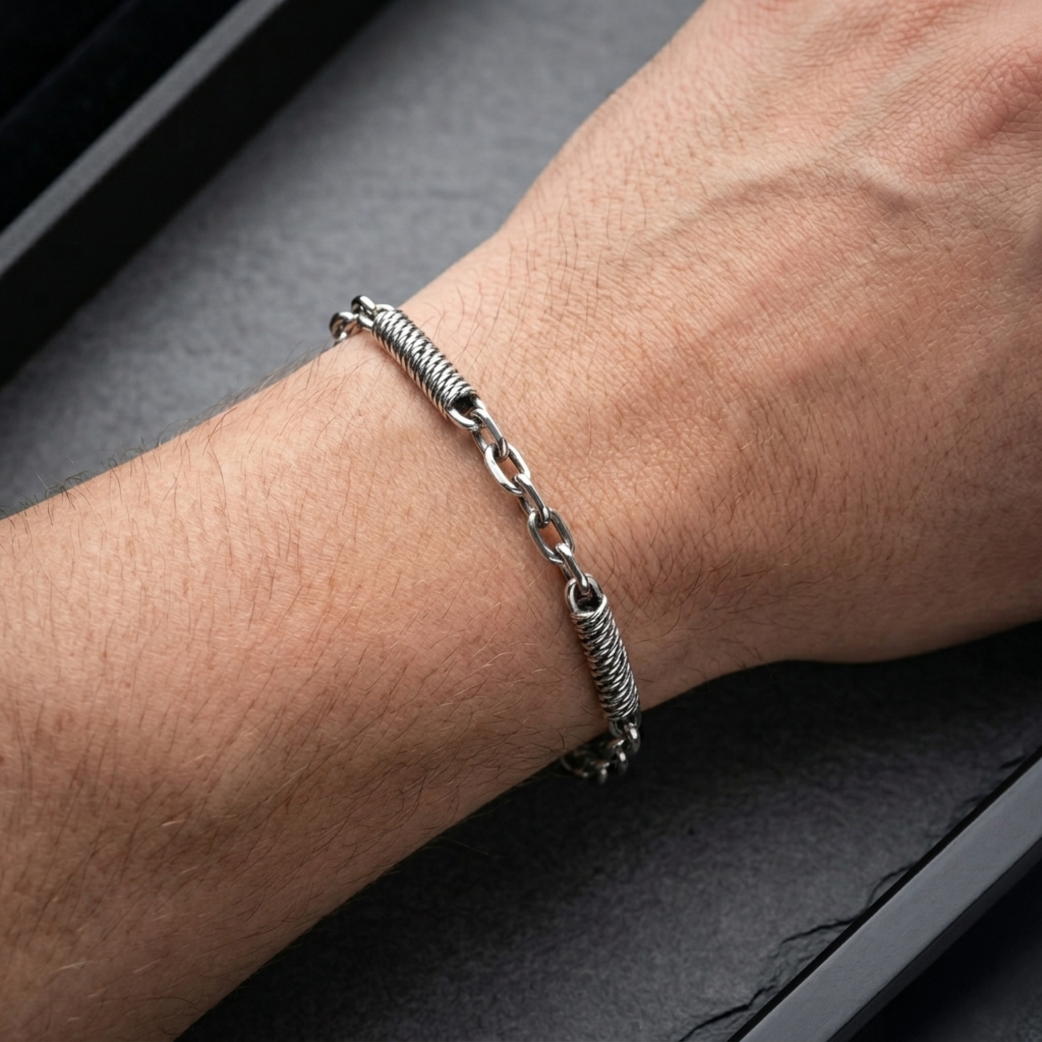 Nahaufnahme eines Ankerarmbands aus 925er Silber mit spiralförmigen Seildraht-Einsätzen am Handgelenk eines Mannes.