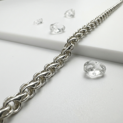 Handgefertigte der eleganten Unisexkette Modell Bismarck-Bach aus 925er Sterling Silber zur Demonstration des plastischen Geflechts auf hellem Untergrund mit transparenten Steinen.
