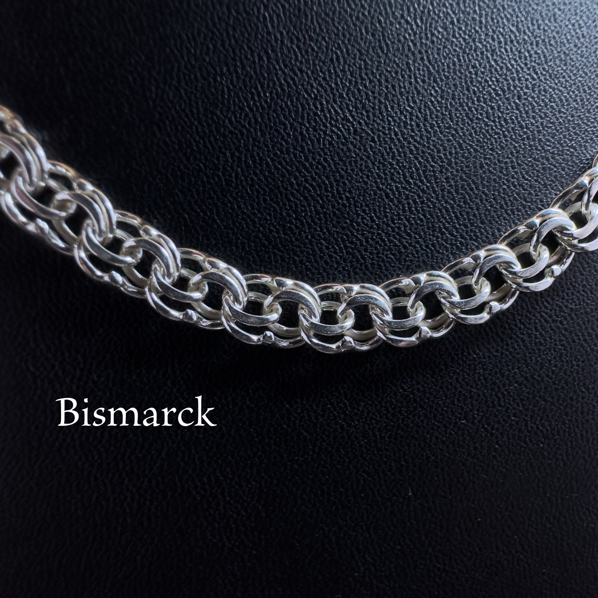 Nahaufnahme der handgefertigten Silberkette Modell Bismarck Flach aus glänzendem 925er Silber auf schwarzem Lederhintergrund

