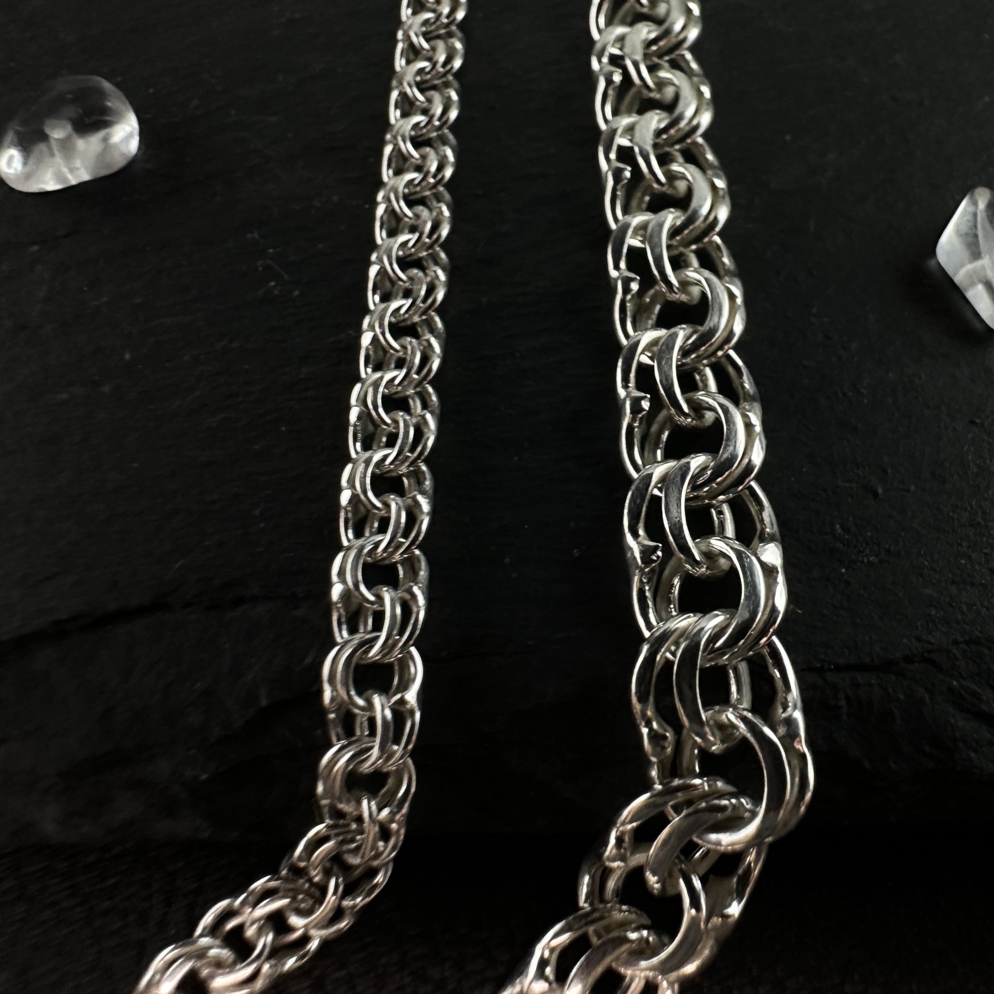 Größenvergleich zweier handgefertigter Silberketten Modell Bismarck Flach aus 925er Silber auf schwarzem Leder mit einer massiven 30 Gramm Kette links und einer feineren 10 Gramm Kette rechts.