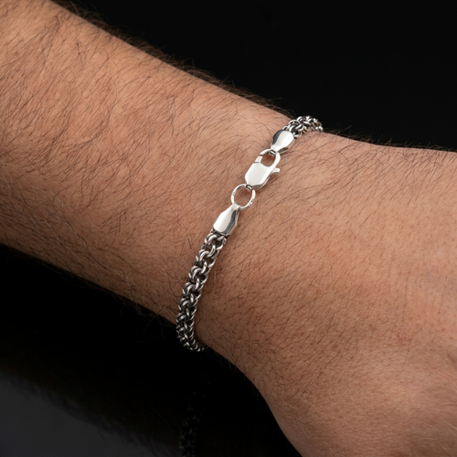 Exklusives handgefertigtes Herrenarmband „Bismarck Rund“ aus 925er Silber mit oxidierter Oberfläche am Handgelenk. Zeigt das massive Geflecht und den robusten Karabinerverschluss in Nahaufnahme.