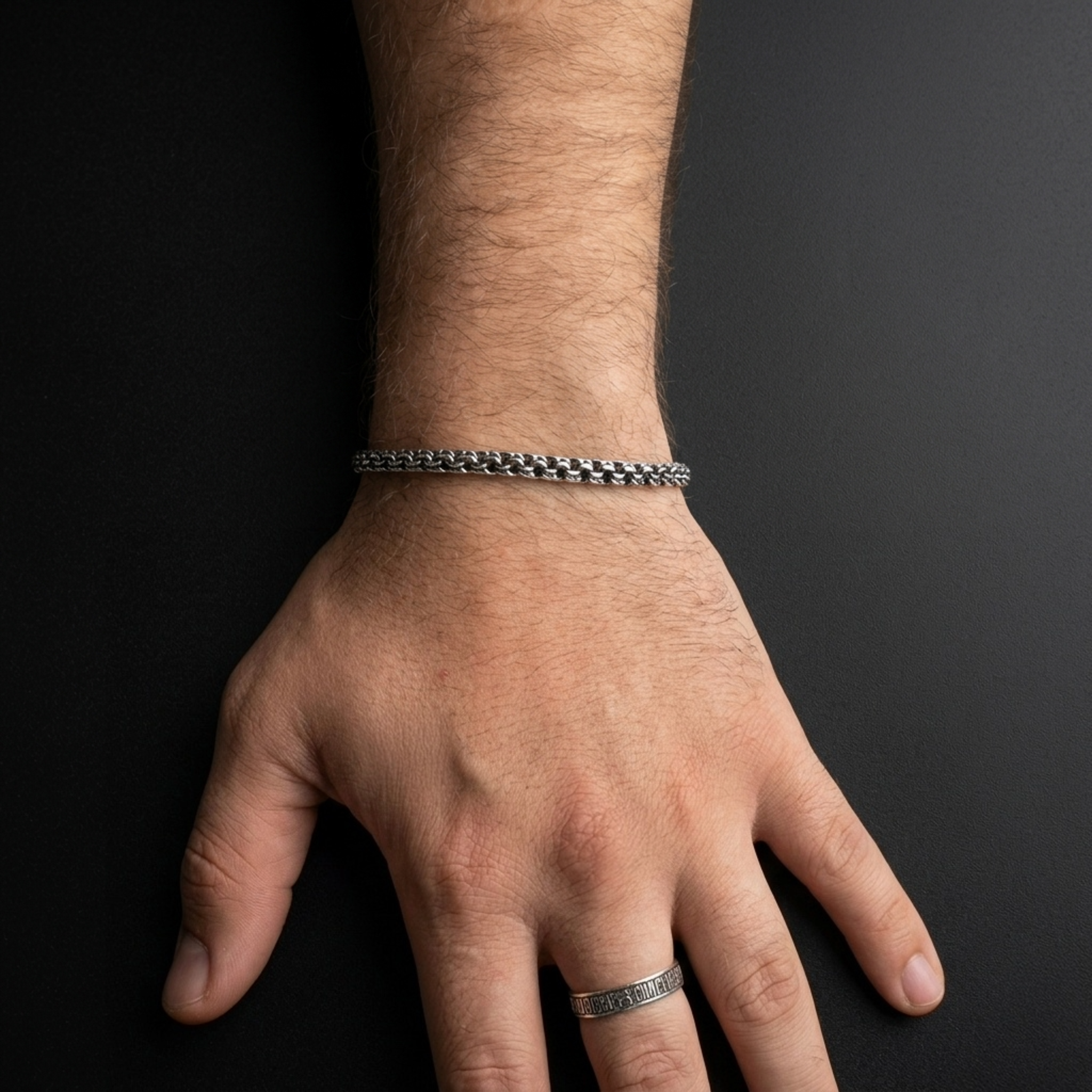 Frontansicht des handgefertigten Silberarmbands Modell „Bismarck Rund“ (925er Silber, oxidiert) am behaarten Herrenhandgelenk. Zeigt das gleichmäßige massive Geflecht.