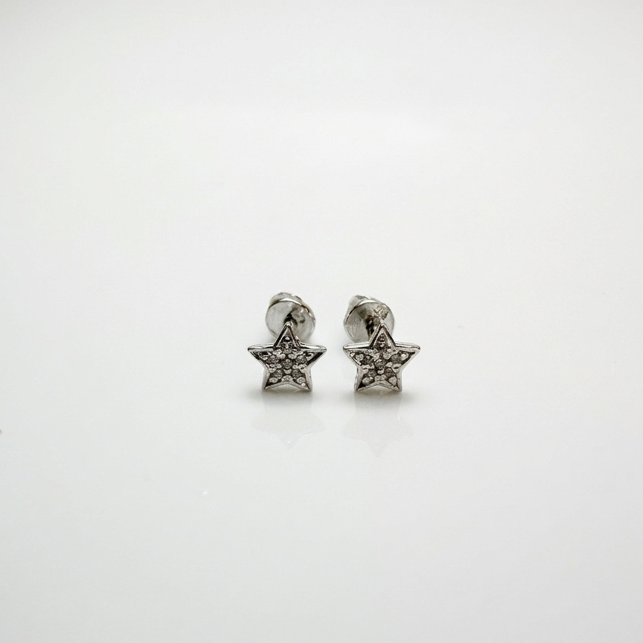 Rhodinierte Echtsilber-Ohrstecker 925 mit glänzendem Schutzfinish gegen Anlaufen, feines Stern-Design mit weißen Steinen aus Zirkonia, fotografiert auf weißem Hintergrund.