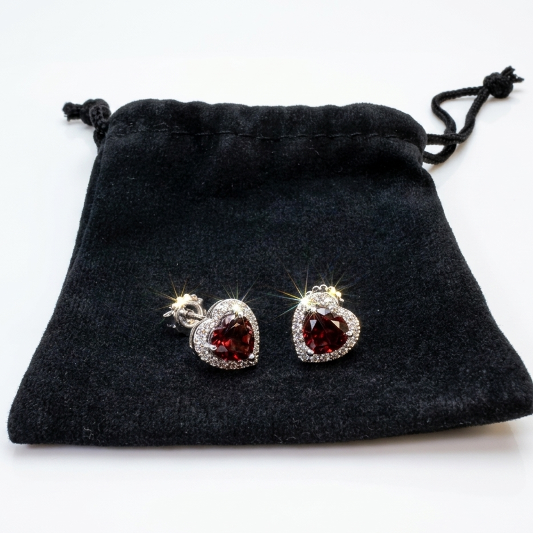 Geschenkfertiges Set: Funkelnde rote Herz-Ohrringe aus Sterlingsilber 925 zusammen mit einem eleganten schwarzen Samtbeutel für Schmuck.
