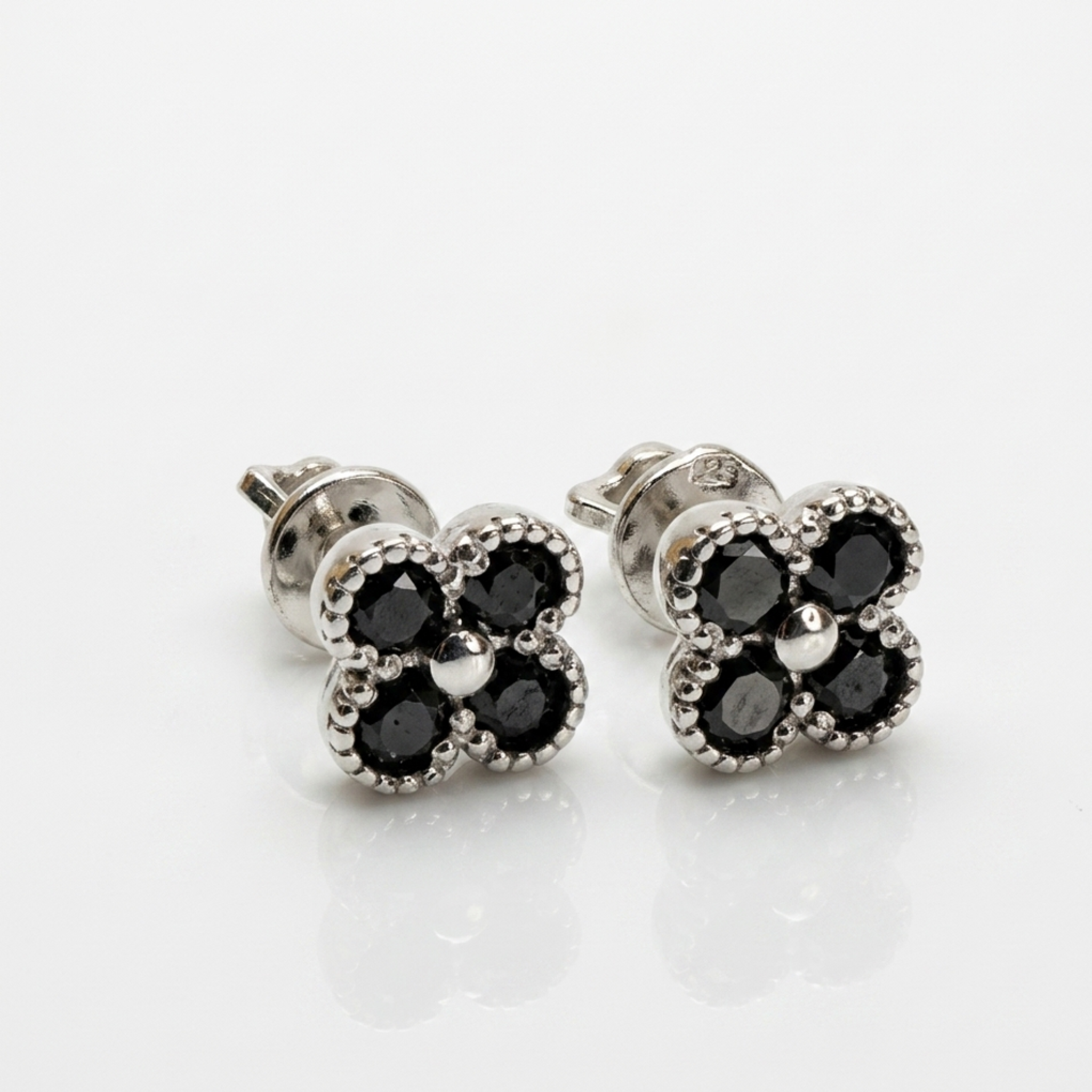 Ohrstecker Kleeblatt aus Silber 925 mit schwarzen Zirkonia-Steinen. Modell mit sicherem Schraubverschluss und rhodinierter Oberfläche auf weißem Hintergrund.
