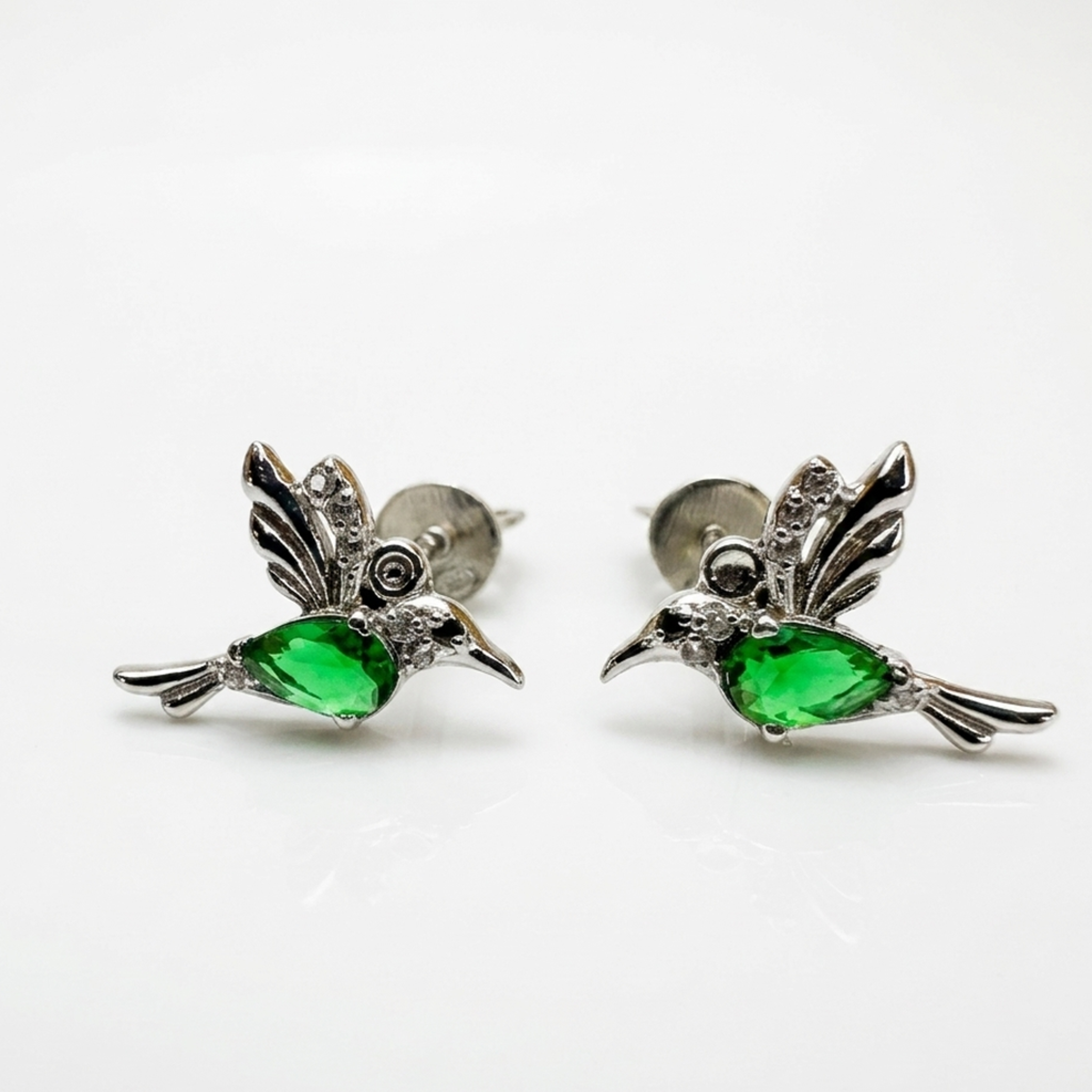 Nahaufnahme von Kolibri-Ohrsteckern aus 925er Silber mit smaragdgrünem Zirkonia-Hauptstein und klaren Akzenten auf weißem Hintergrund.