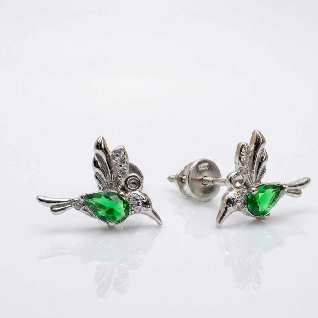 Zwei glänzende Vogel-Ohrringe aus rhodiniertem Silber 925 mit facettierten grünen Zirkonia-Tropfen im Fokus vor hellem Studiohintergrund.