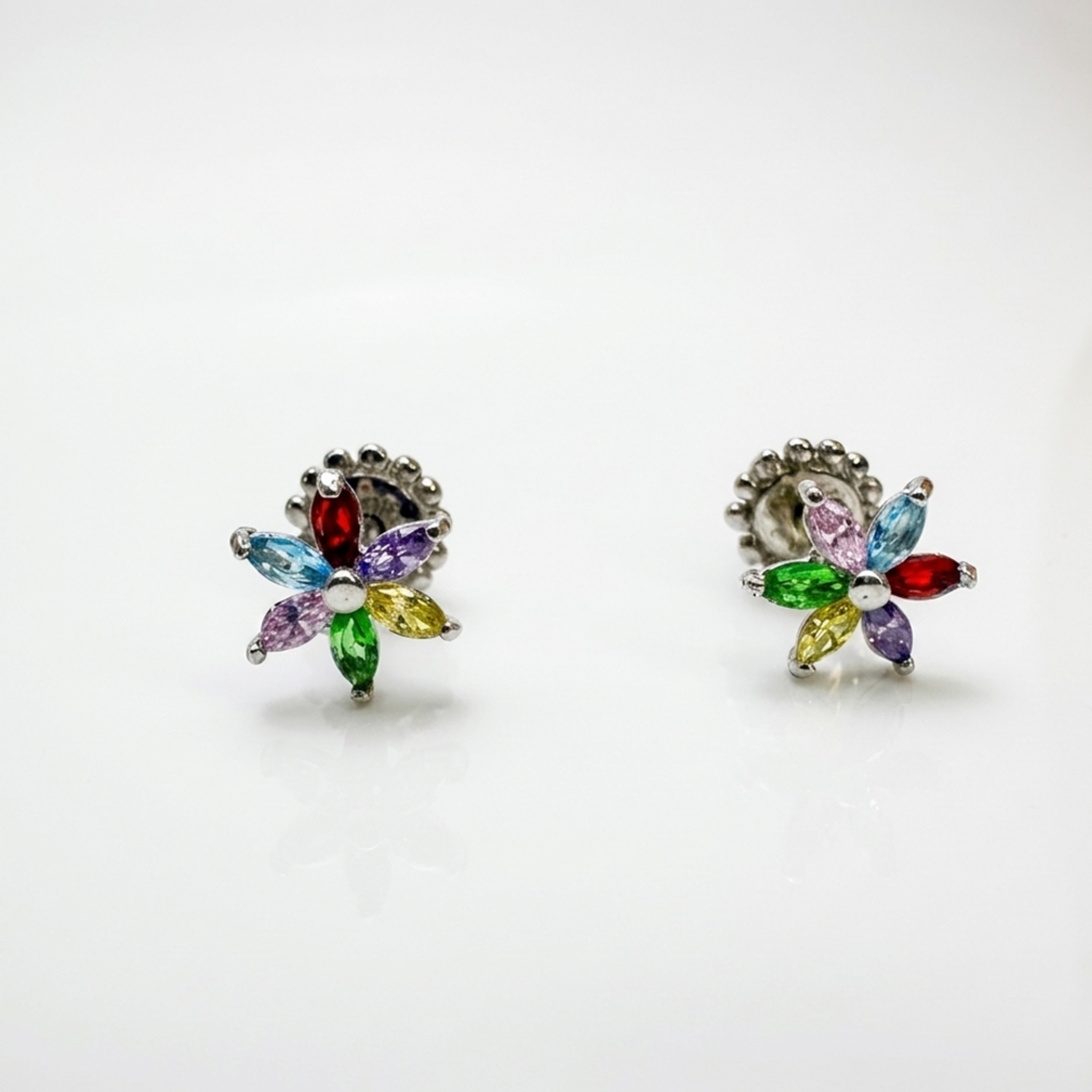 Zwei glänzende Blüten-Ohrringe aus 925er Sterling Silber mit Rhodium-Beschichtung und bunten Zirkonias im Marquise-Schliff vor hellem Studiohintergrund.