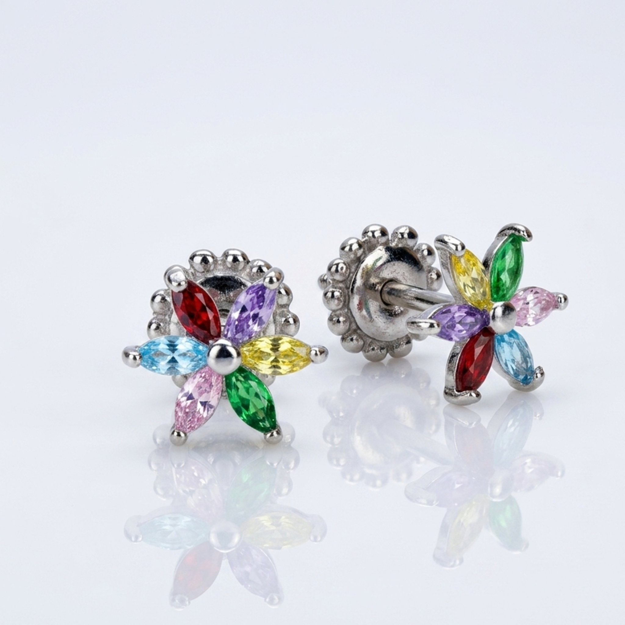 Makroaufnahme von bunten Silberohrringen in Blütenform aus 925er Sterling Silber, rhodiniert, in Frontal- und Seitenansicht auf weißer Studio-Oberfläche.