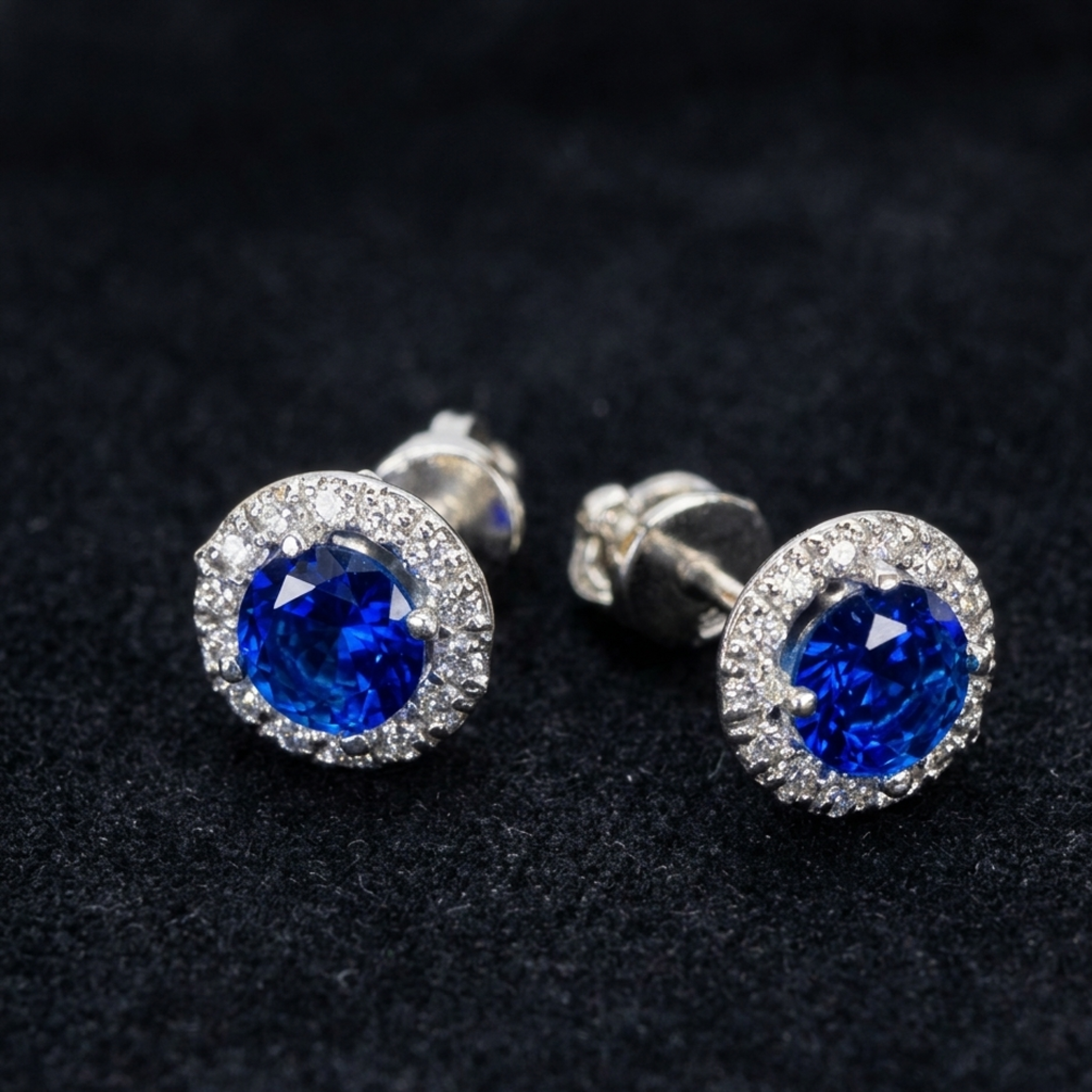 Detailansicht von blauen Halo-Ohrringen aus 925er Silber mit funkelndem Steinkranz und sichtbarer Schraubverbindung auf schwarzem Samt.