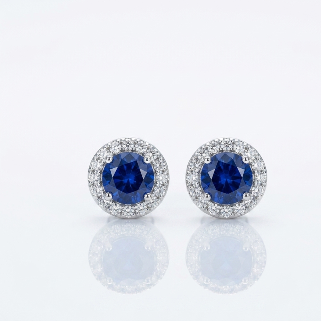 Nahaufnahme von zwei funkelnden Silber-Ohrsteckern mit tiefblauen Zentralsteinen und feinem Steinkranz auf reinweißem Grund.