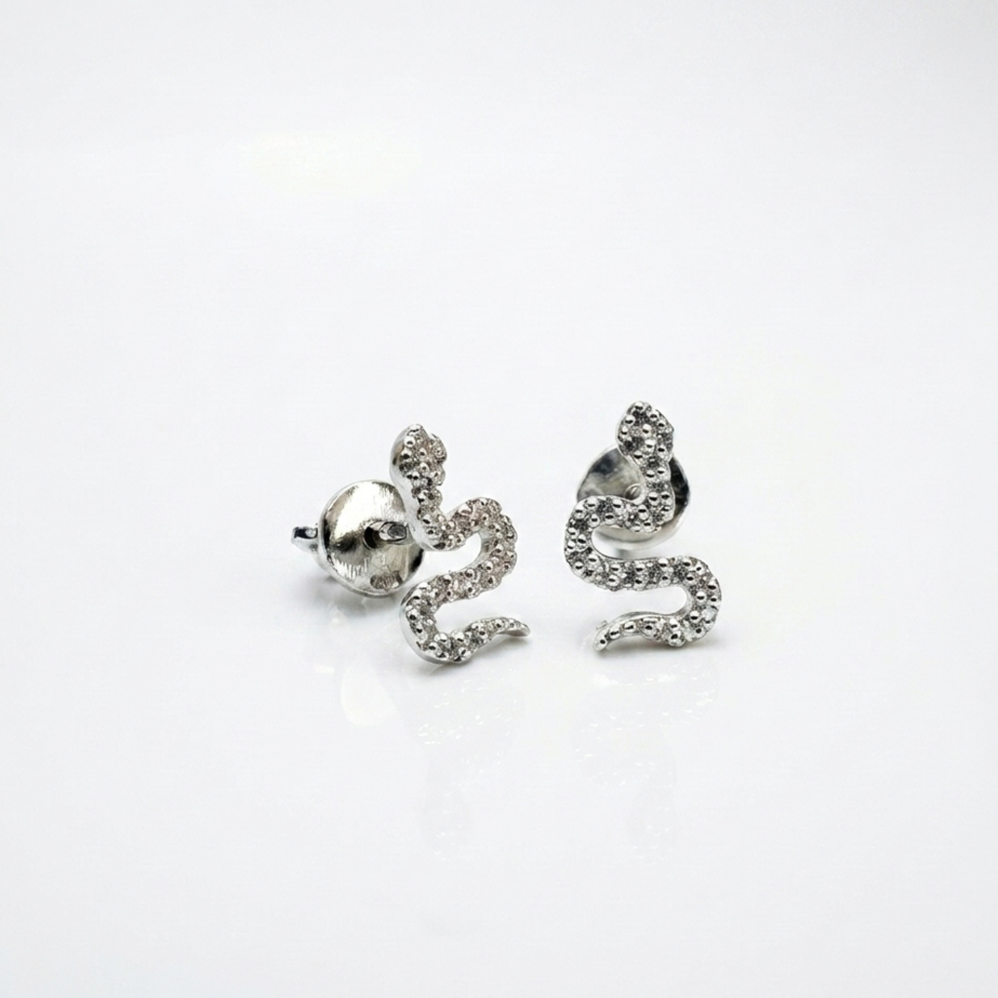 Handgefertigte Silber-Ohrstecker „Schlange“ aus 925 Sterling Silber rhodiniert mit weißen Zirkonia-Steinen und Schraubverschluss auf weißem Hintergrund.