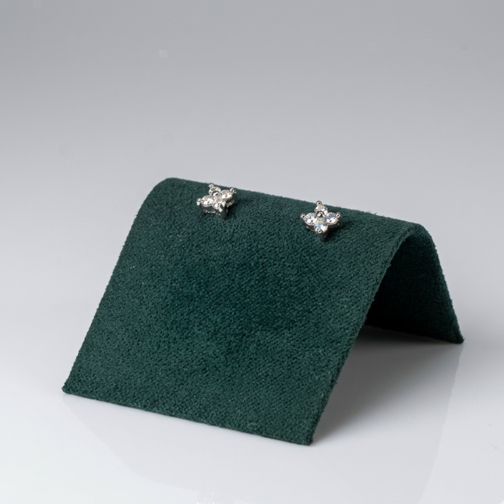 Handgefertigter Designerschmuck: Rhodinierte Ohrringe aus 925er Sterling Silber mit vier Steinen in Kreuzform auf einer exklusiven dunkelgrünen Samtpräsentation.
