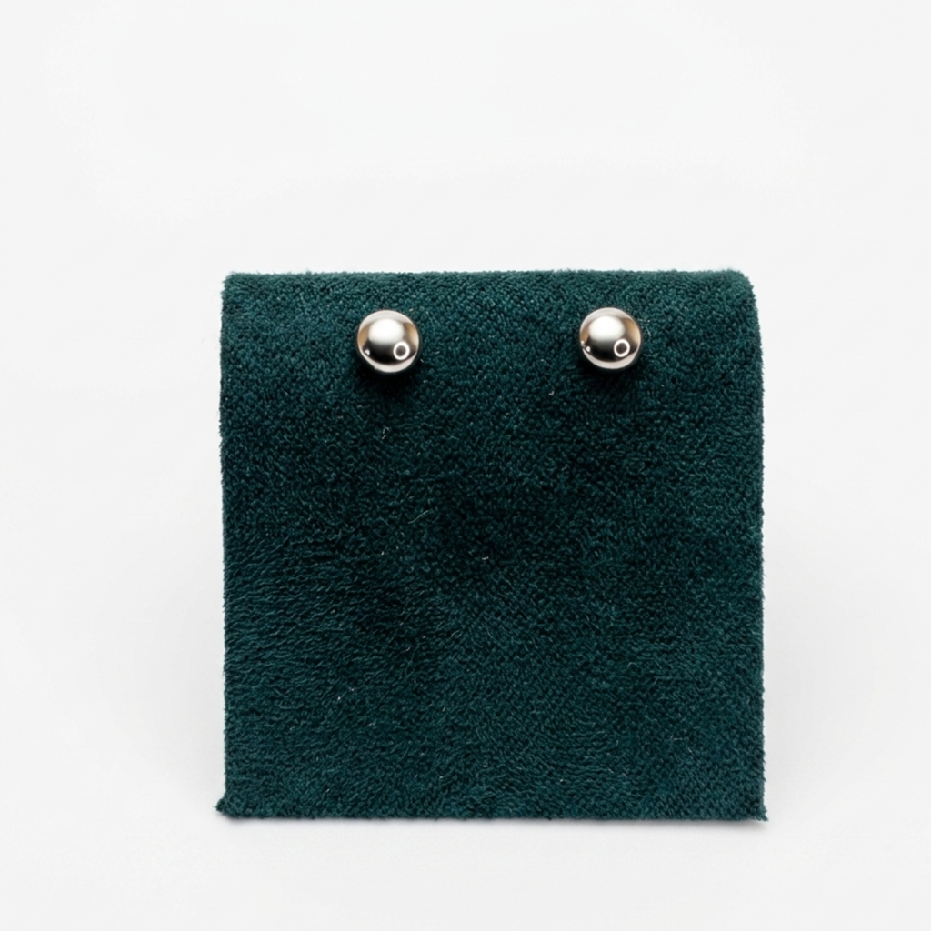 Nahaufnahme der Vorderansicht von minimalistischen Halbkugel-Ohrringen aus echtem Silber auf einem edlen grünen Samtaufsteller.