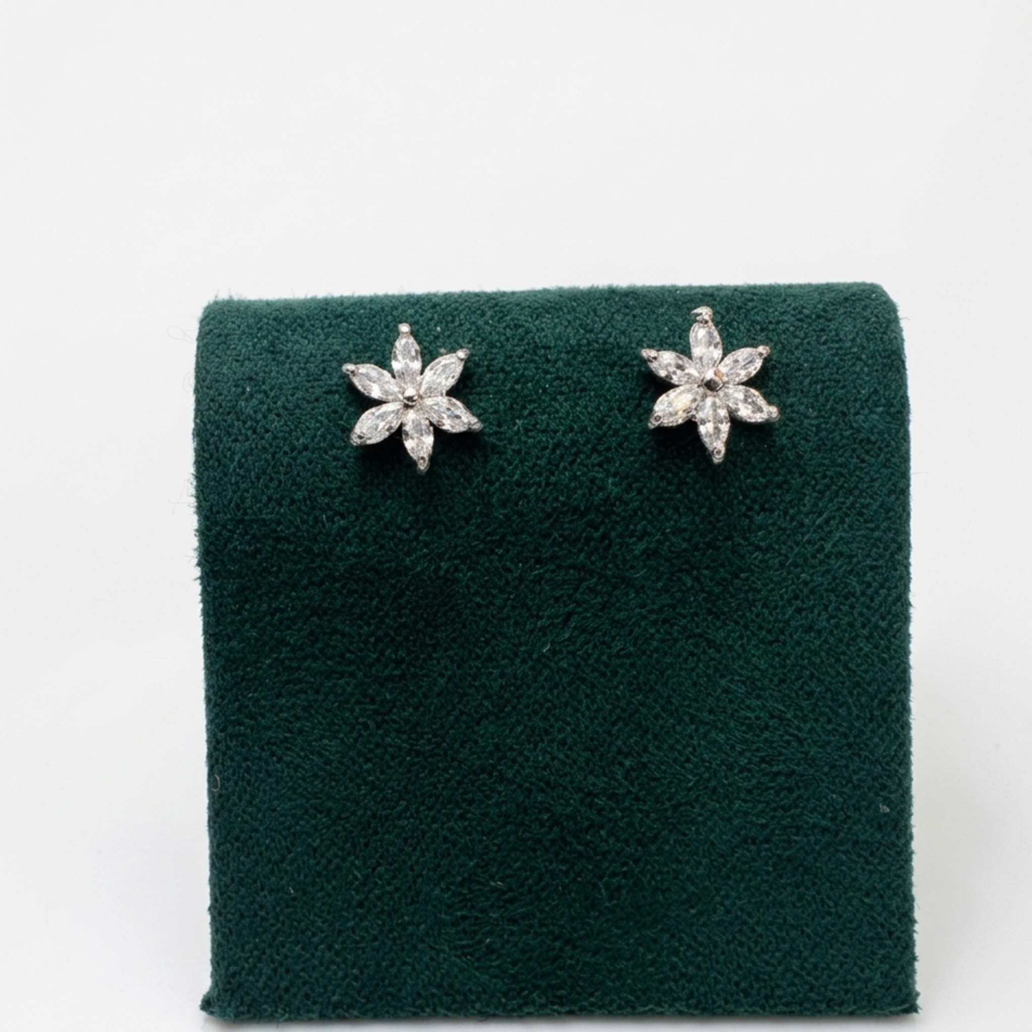 Nahaufnahme der Vorderansicht von filigranen Blüten-Ohrringen mit klaren Zirkonia im Marquise-Schliff auf einem edlen grünen Samtaufsteller.