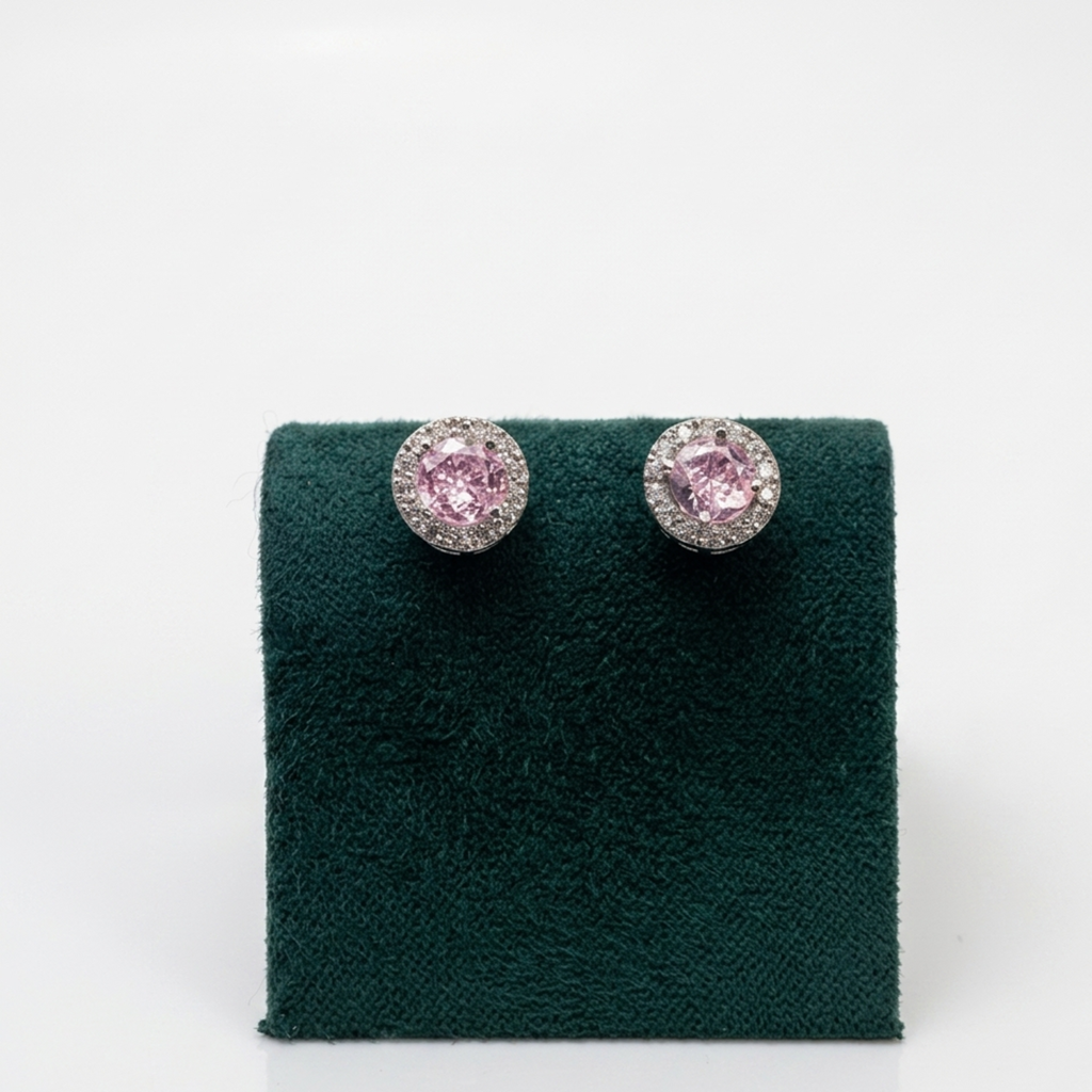 Nahaufnahme der Vorderansicht von edlen ovalen Silberohrringen mit einem großen rosa Zirkonia-Zentralstein auf einem grünen Samtaufsteller.