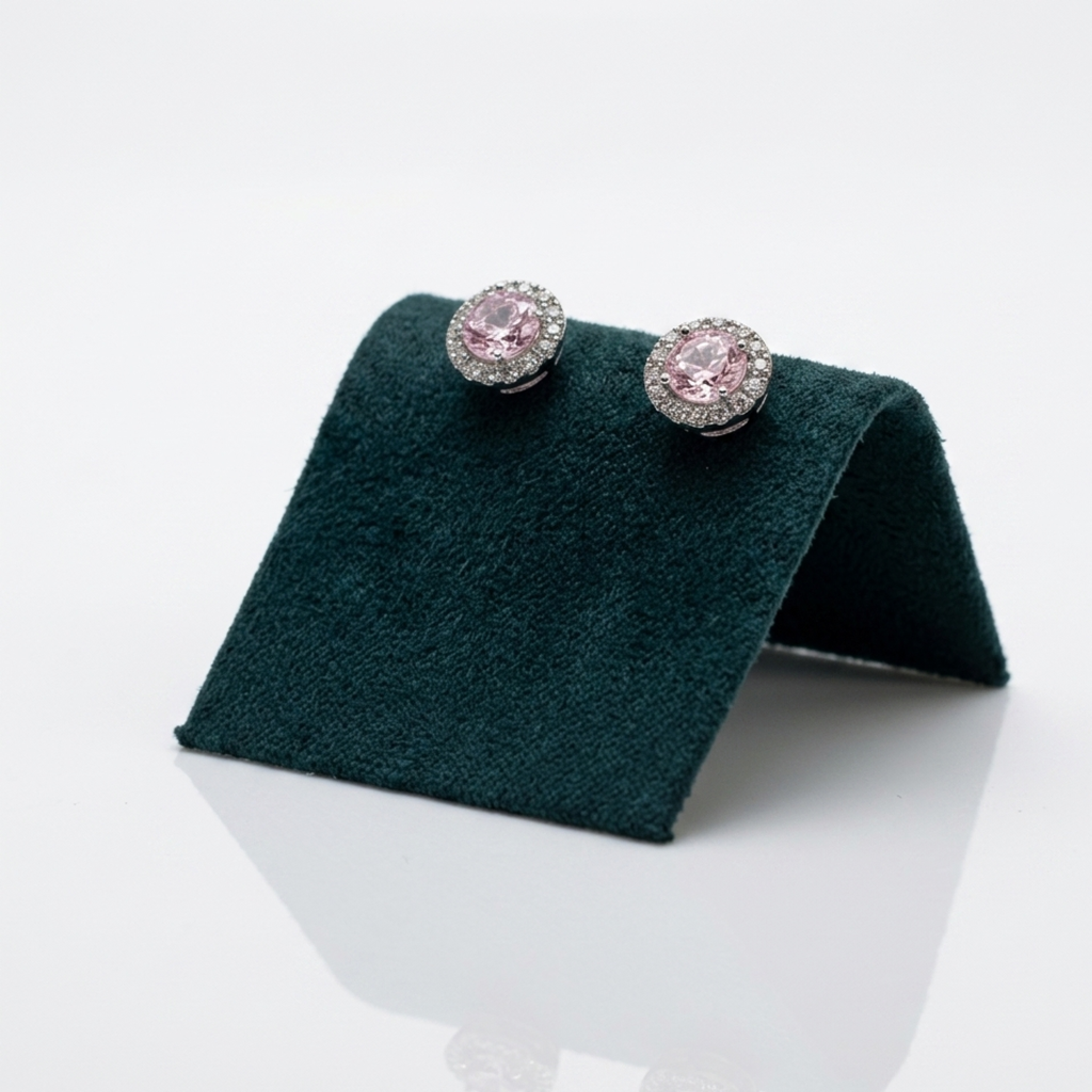 Handgefertigter Designerschmuck: Rhodinierte Solitär-Ohrringe mit ovalen, rosafarbenen Zirkonia auf einer exklusiven dunkelgrünen Samtpräsentation.