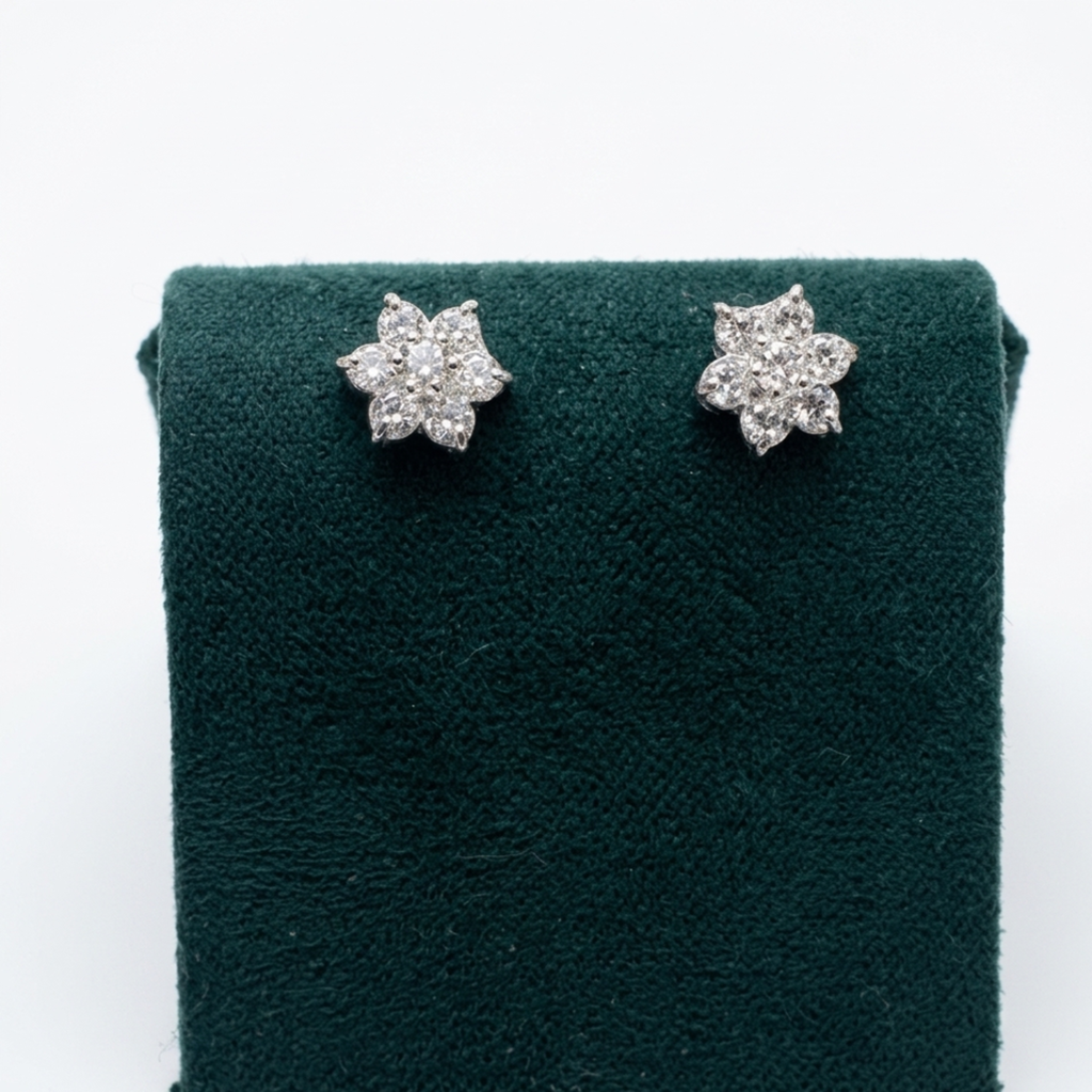 Nahaufnahme der Vorderansicht von filigranen Blüten-Ohrringen aus Silber mit runden Zirkonia-Steinen auf einem edlen grünen Samtaufsteller.