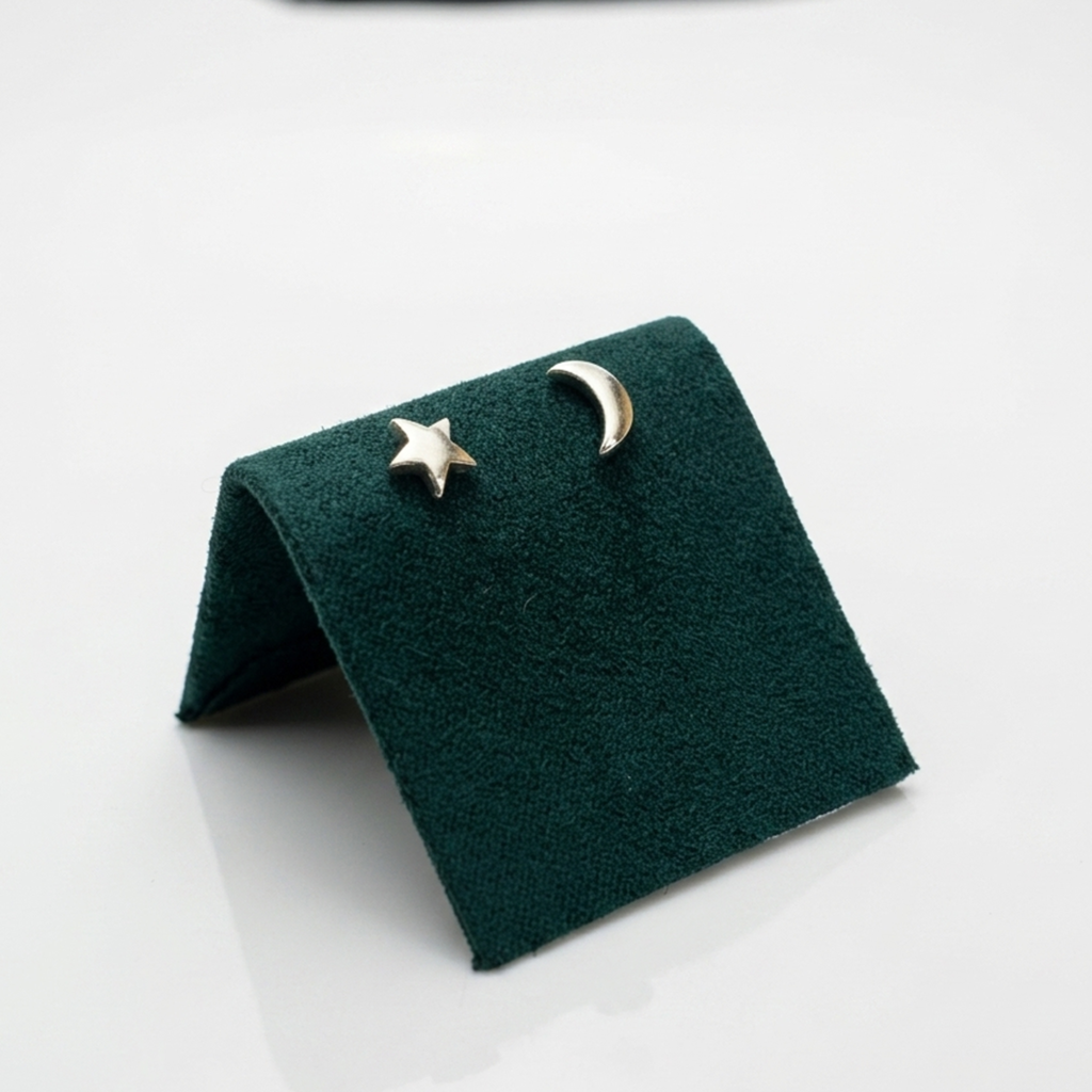 Handgefertigter Designerschmuck: Rhodinierte Astro-Ohrringe ohne Steine aus echtem Silber auf einer exklusiven dunkelgrünen Samtpräsentation.