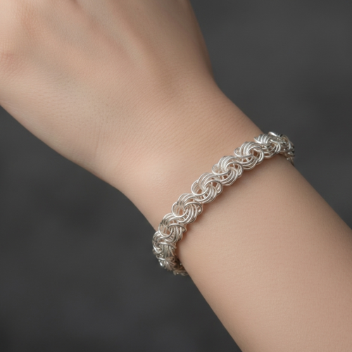 Detailansicht eines handgefertigten Damenarmbands Modell Rose aus 925er Silber an einem Handgelenk vor dunklem Hintergrund.