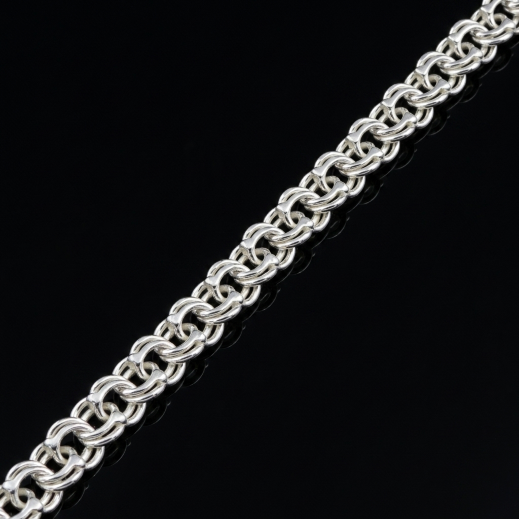 Silberarmband „Russischer Bismarck“ aus 925 Sterlingsilber diagonal liegend auf schwarzer Spiegeloberfläche.