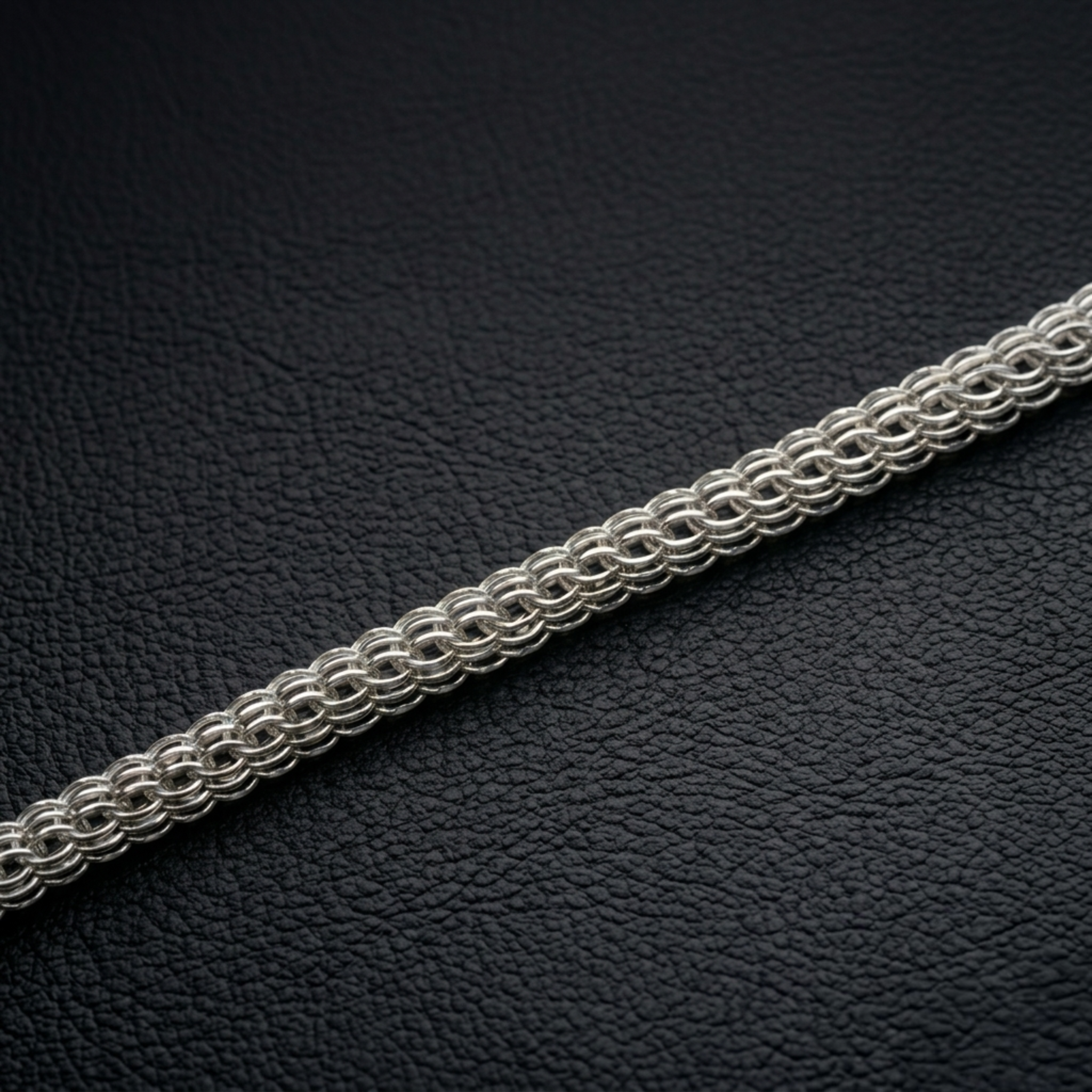 Detailansicht einer unbeschichteten Silberkette Modell Super Python aus 925er Silber auf schwarzem Lederhintergrund zur Demonstration der feinen handwerklichen Struktur und des Kontrasts.
