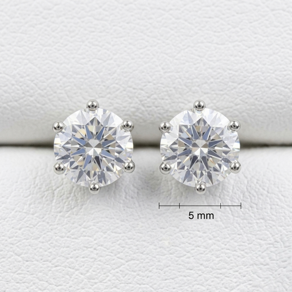 Detailansicht von rhodinierten 925 Sterling Silber Ohrringen mit runden Zirkonia-Steinen auf eleganter weißer Lederstruktur.