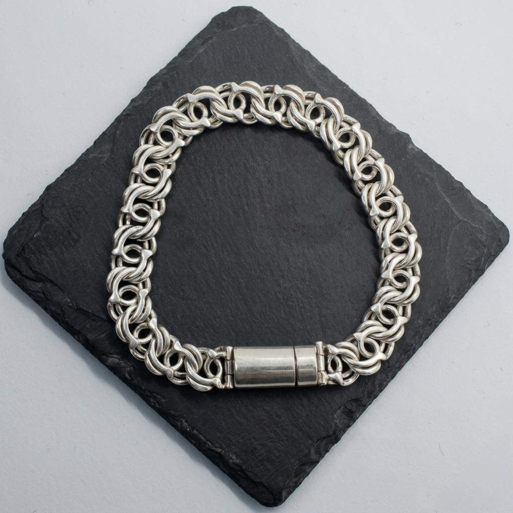 Detailaufnahme der Rückseite eines handgearbeiteten 925er Sterling Silberarmbands zur Veranschaulichung des glatten Zylinder-Verschlusses auf dunklem Stein.